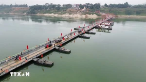 People and vehicles travel across the Lo river pontoon bridge on the morning of February 16. (Photo: VNA)