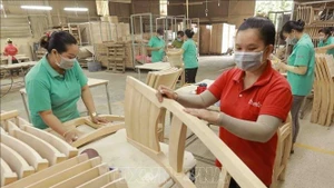 Workers make wooden furniture for export to the US, UK and EU markets at the factory of the Thiet Dan Two-Member Company Limited. (Photo: VNA)