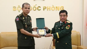 Major General Nguyen Ba Luc (R) presents a gift to Lieutenant General Nim Balene. (Photo: qdnd.vn)