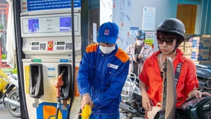 A motorcyclist has her vehicle refilled at a petrol station of Petrolimex. (Photo: VNA)