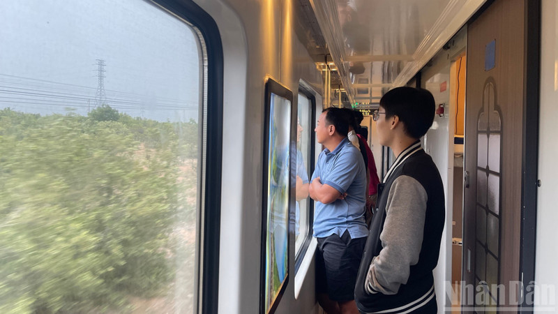 Passengers enjoy the scenery through the carriage windows.