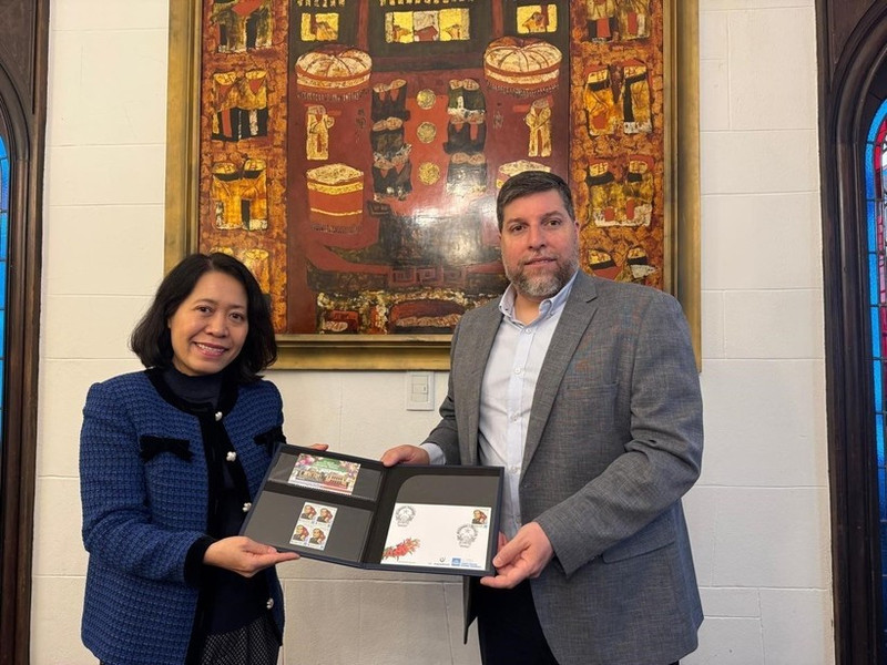 MP Victor Aldaya presents Ambassador Ngo Minh Nguyet with a set of stamps issued by Uruguay's National Post Office in December 2013, commemorating the 20th anniversary of Viet Nam-Uruguay diplomatic relations. (Photo: VNA)