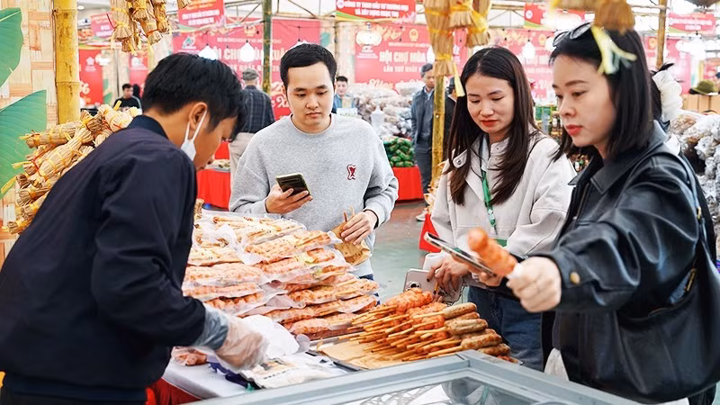 Customers use mobile phones to trace the origin of food products. (Photo: NGUYET ANH)