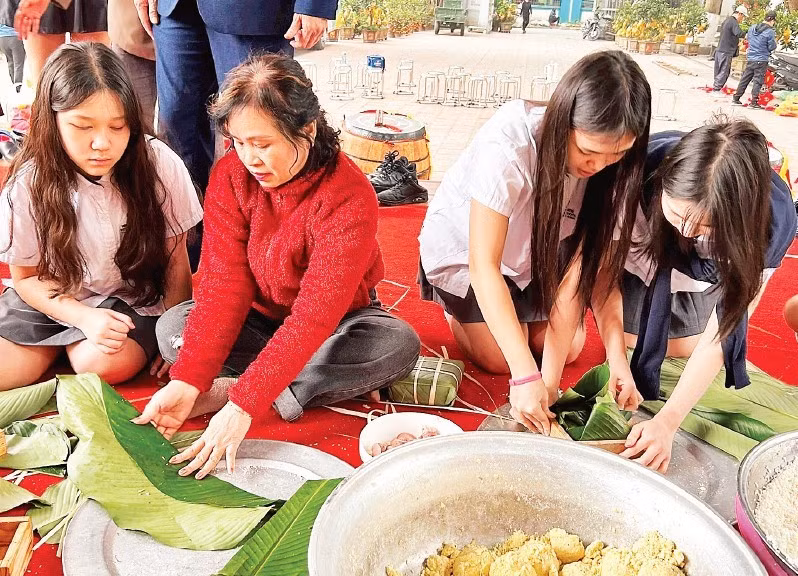 Students experience wrapping banh chung with members of the Intergenerational Self-Help Club in Khuong Dinh Ward (Ha Noi City).