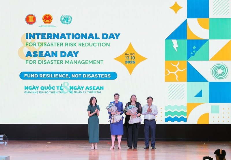 Deputy Minister of Agriculture and Environment Nguyen Hoang Hiep and Pauline Tamesis, UN Resident Coordinator in Viet Nam present flowers to welcome WHO and IOM as new members of the disaster risk reduction partnership. (Photo: VNA)