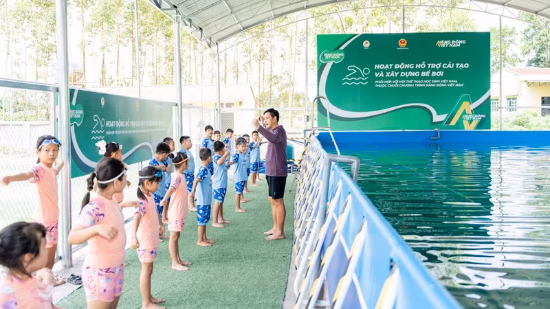 A teacher guides student through warm-up exercises before they enter the pool.
