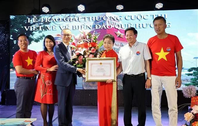 Vietnamese Ambassador to Germany Vu Quang Minh presents a certificate of merit and flowers to Bui Thi Thu Minh, head of the Vietnamese Liaison Committee in Europe "For Viet Nam's Seas and Islands", President of the Truong Sa Club in Germany. (Photo: VNA)