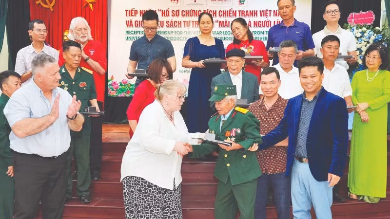 Representatives of Texas Tech University hand over documents to war veteran and wounded soldier Do Xuan Thuyen.