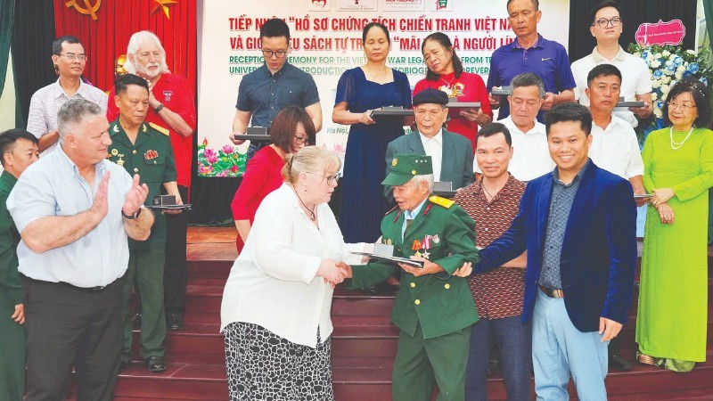 Representatives of Texas Tech University hand over documents to war veteran and wounded soldier Do Xuan Thuyen.