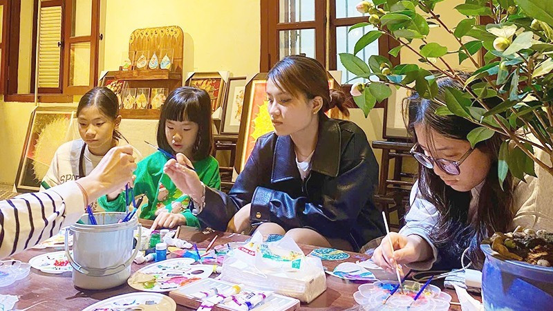 Young people try their hand at creative work on Bodhi leaves.