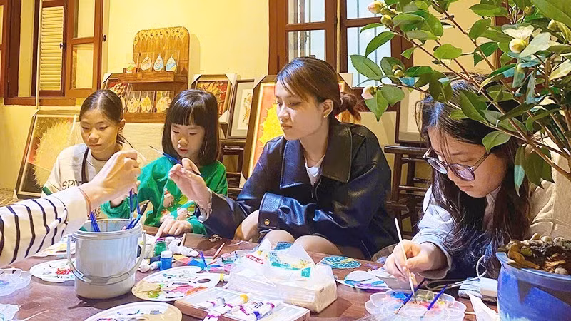 Young people try their hand at creative work on Bodhi leaves.