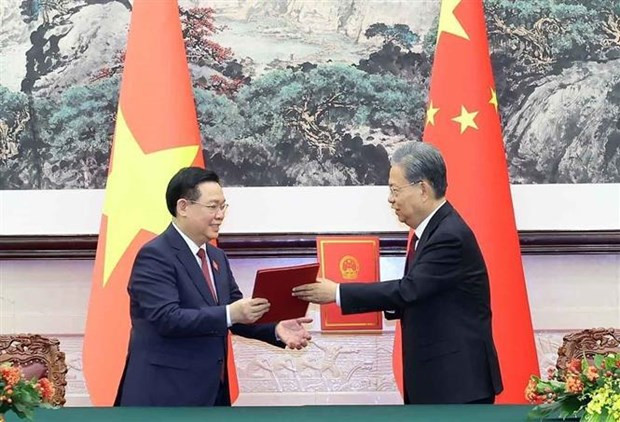 Hue and Zhao exchange the new cooperation agreement between the Vietnamese NA and the National People’s Congress of China. (Photo: VNA)