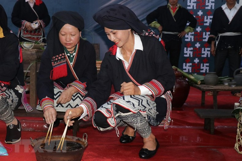 Dao artisans demonstrate how to dye fabrics with indigo water. (Photo: Huu Quyet/VNA)