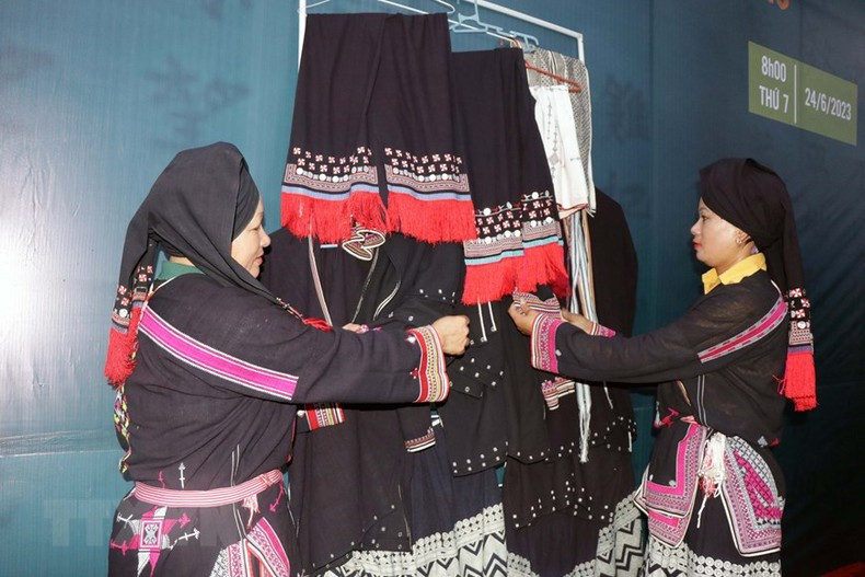 The artisans introduce the traditional costumes of the Dao ethnic group. (Photo: Huu Quyet/VNA)