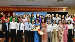 Chairman of the State Committee for Overseas Vietnamese (L) presents flowers to representatives of Vietnamese language teachers abroad. (Photo: VNA)