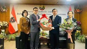 Vietnamese Ambassador Vu Le Thai Hoang congratulates Lao Ambassador Khampheng Douangthongla. (Photo: NDO)