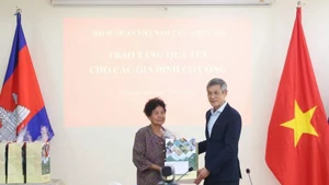 Vietnamese Ambassador Nguyen Minh Vu to Cambodia Nguyen Minh Vu (right) presents Tet gifts to Ha Thi E, who contributed to the resistance war against the US and was awarded a certificate of merit by the Prime Minister of Viet Nam in 2009. (Photo: VNA)