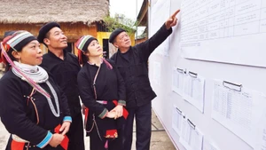 Voters review the list of candidates publicly posted at the cultural house of Nam Dam Hamlet, Quan Ba Commune (Tuyen Quang Province) (Photo: VNA)