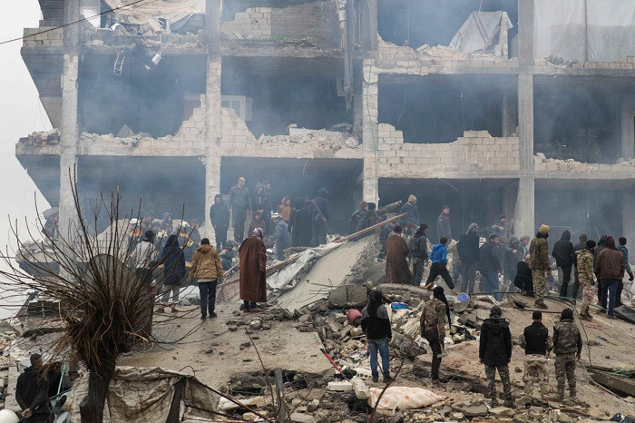 People gather as rescuers search for survivors under the rubble, following an earthquake, in rebel-held town of Jandaris, Syria. (Credit: Reuters Photo)