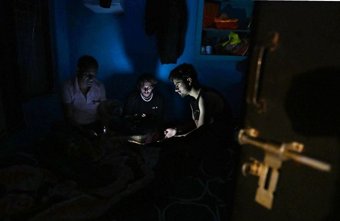 People watch their mobile phones in a room during a blackout enforced by authorities in Srinagar city, Indian-controlled Kashmir, on May 9, 2025. Tensions have remained as flare-ups between Pakistan and India have entered the third day. (Photo: Xinhua)