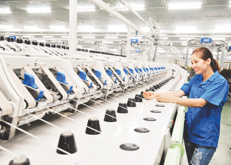 A worker of Eight March Textile Company Limited is operating a yarn production line.