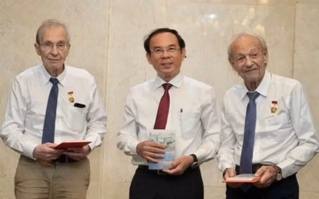 Nguyen Van Nen, Politburo member and Secretary of the Ho Chi Minh City Party Committee, presents the HCM City Badge to Olivier Parriaux and Bernard Bachelard at the meeting. 