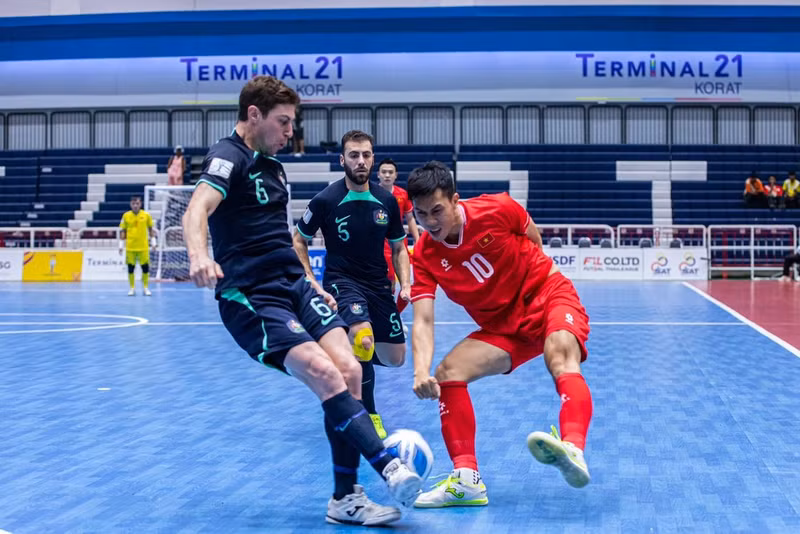 A Vietnamese futsal player (red) faces two Australian players at the semi-final match of the ASEAN Futsal Championship 2024 on November 8. (Photo: VNA)