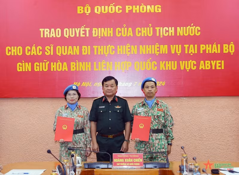 Deputy Minister of National Defence Senior Lieutenant General Hoang Xuan Chien (right) hands over the President's decision to two officers (Photo: qdnd.vn)