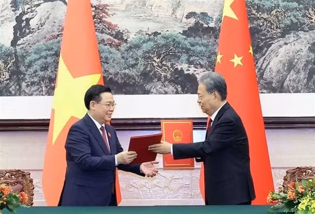 NA Chairman Vuong Dinh Hue (L) and Chairman of the Standing Committee of the National People's Congress of China Zhao Leji exchange the new cooperation agreement between the Vietnamese NA and the National People’s Congress of China. (Photo: VNA)