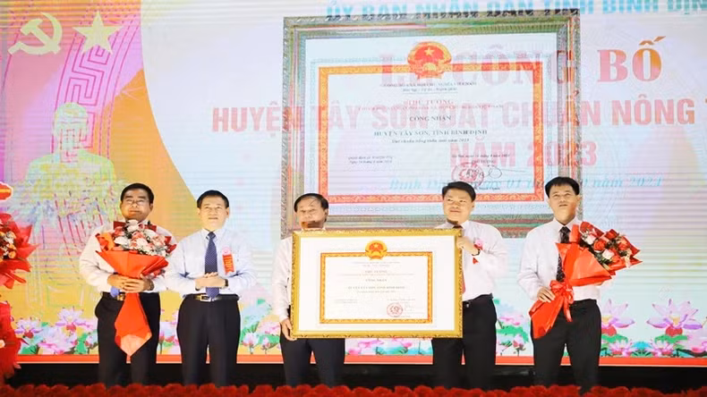 Deputy PM Ho Duc Phoc presents the Certificate of recognition of Tay Son District as a new-style rural district to the leaders of the district