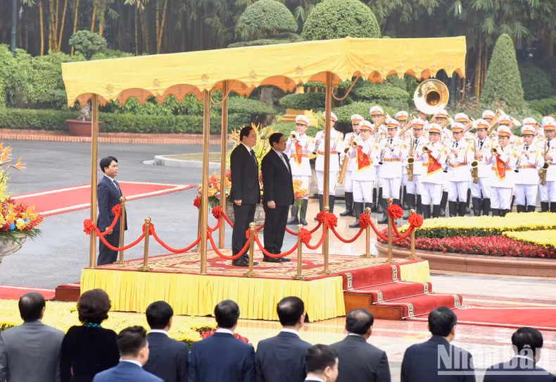 Prime Minister Pham Minh Chinh and Lao Prime Minister Sonexay Siphandone perform the flag salute ceremony.