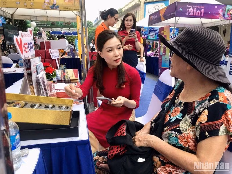 A bank employee guides a woman on how to make non-cash payments. (Photo: NDO)