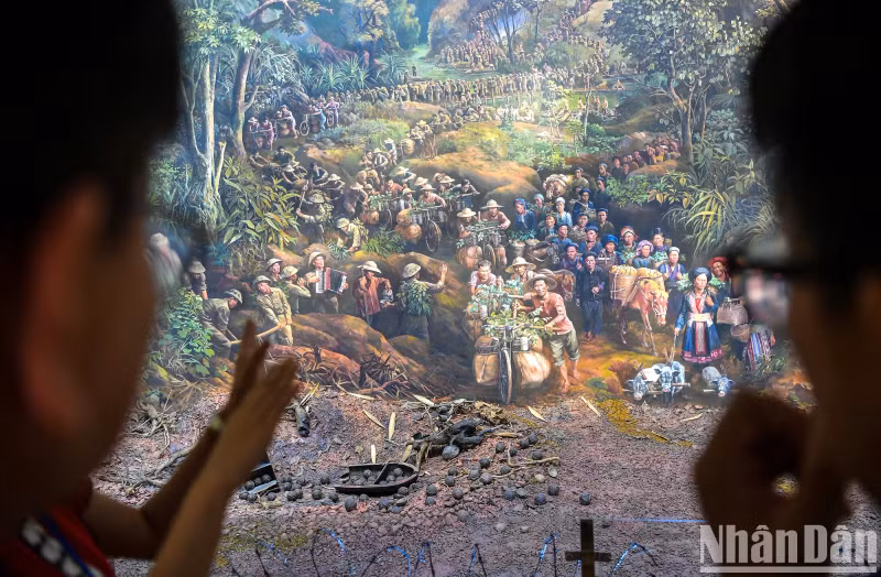 The tour guide leads viewers to each segment of the painting. In the photo is the first scene "All the people go to war" with images of overlapping groups of people, soldiers carrying goods, climbing mountains and wading streams to provide food for the front line.
