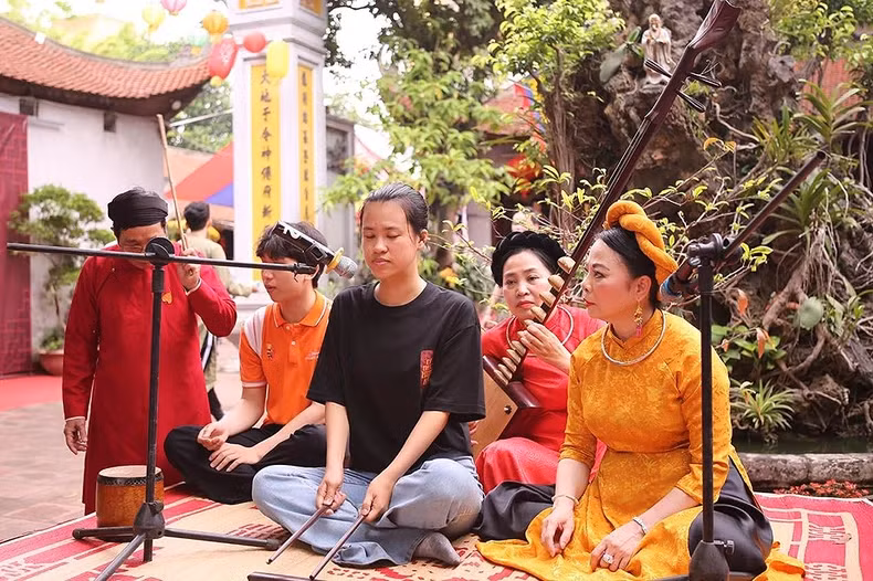 A young person participates in the experience of playing traditional musical instruments on the campus of Bich Cau Dao Quan. A young person participates in the experience of playing traditional musical instruments on the campus of Bich Cau Dao Quan.