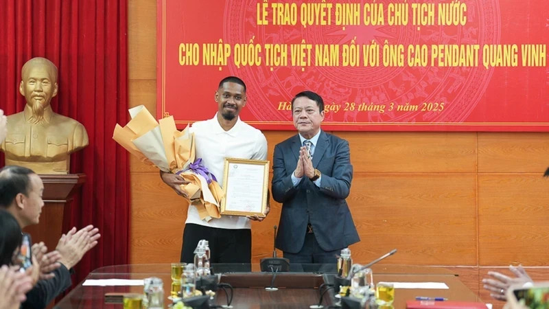 Representative of Hanoi Department of Justice presents the Vietnamese nationality certificate to football player Cao Pendant Quang Vinh. (Photo: PHAN THACH)