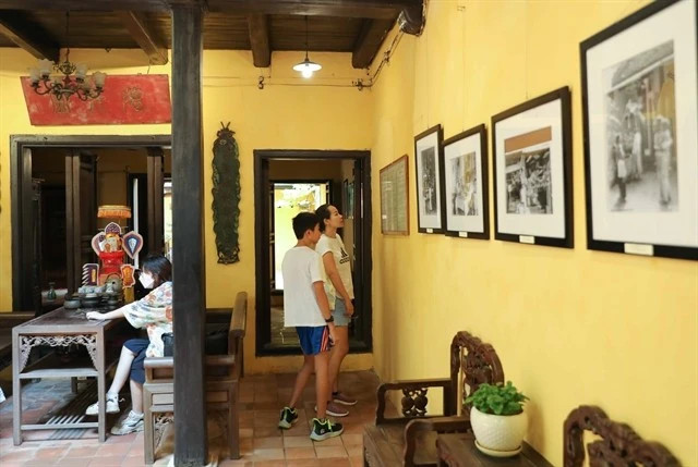 Tourists view photos exhibited in the heritage house on 87 Ma May street, Hanoi. (Photo: VNA)