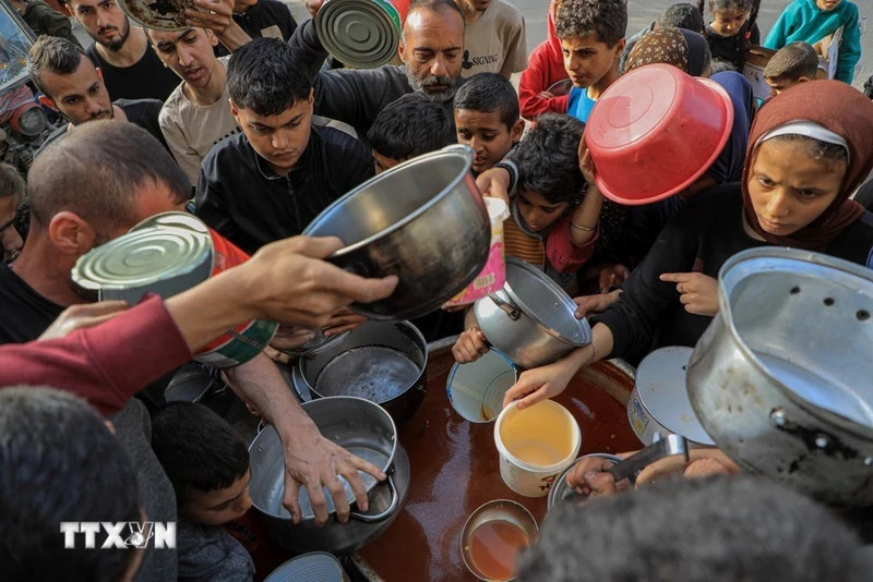 People wait to receive food aid in Rafah City, southern Gaza Strip on March 30, 2024. (Photo: Xinhua/VNA)