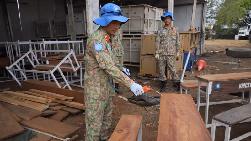 A member of Viet Nam’s Engineering Unit Rotation 3 fabricates a student desk-bench set from repurposed materials.
