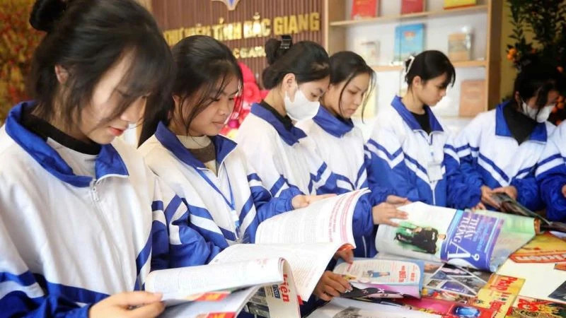 Pupils reading books at an exhibition booth celebrating the 50th anniversary of the Liberation of the South and National Reunification at Bac Giang Library.