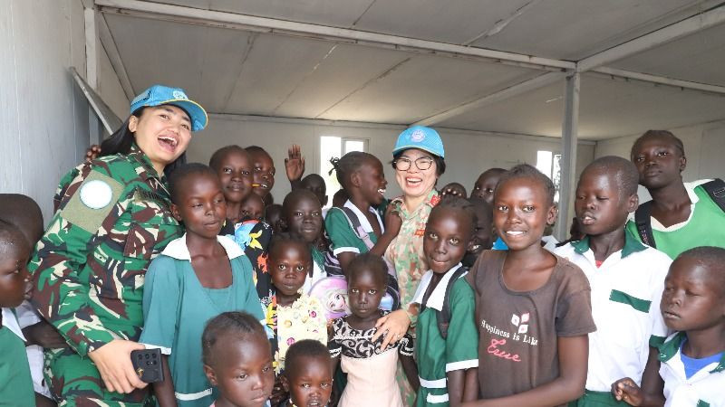 Head of Civil-Military Coordination Office at UNISFA takes a souvenir photo with students of Abyei Primary School.