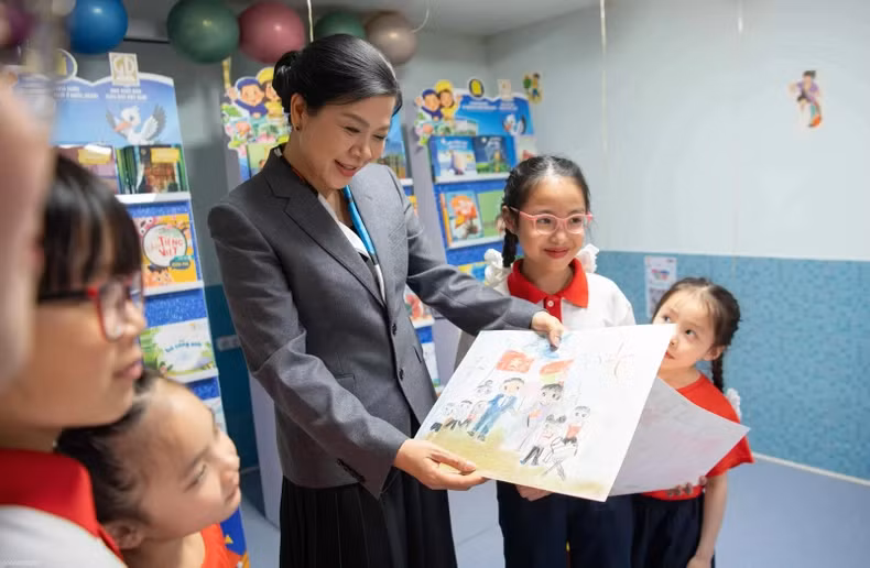 The children proudly show their drawings to Ngo Phuong Ly.