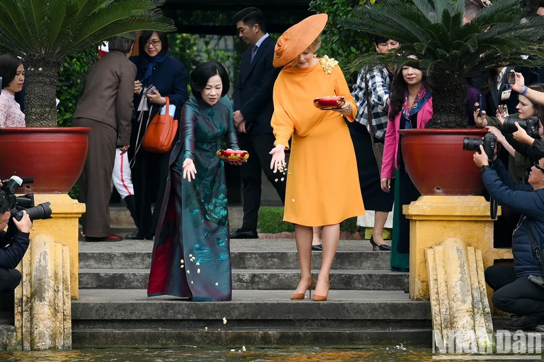 Queen Mathilde joins First Lady Nguyen Thi Minh Nguyet in feeding fish in Uncle Ho’s pond at the President Ho Chi Minh Memorial Site on April 1. (Photo: NDO)
