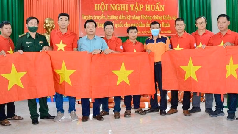 Representatives of Nguoi Lao Dong Newspaper, the Nam Dinh provincial fisheries sub-department and the Maritime Search and Rescue Coordination Centre for Zone 1 present flags to the fishermen.