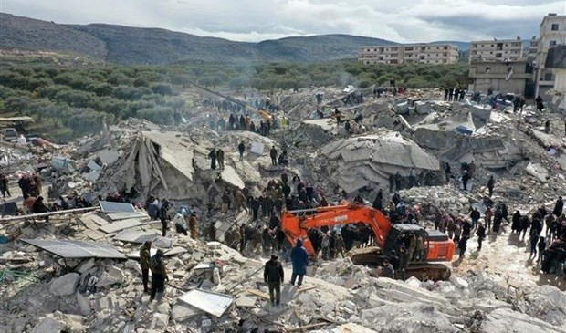 Rescuers and volunteers search for victims and survivors trapped in the rubble after a strong earthquake in the village of Besnia, near the town of Harim, Idlib province Syria, bordering Turkey. (Photo: AFP/VNA)