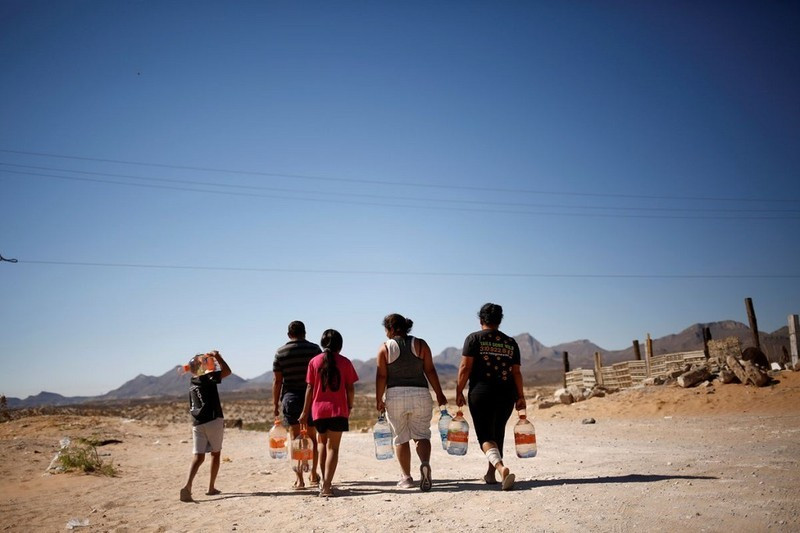 People carry bottles of drinking water given by high school students in support of neighbourhoods with lack of potable water in Ciudad Juarez, Mexico, May 28, 2021. (Photo: Reuters)