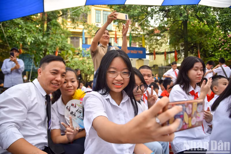 A school girl takes a selfie photo with her friends during the new academic year opening ceremony.