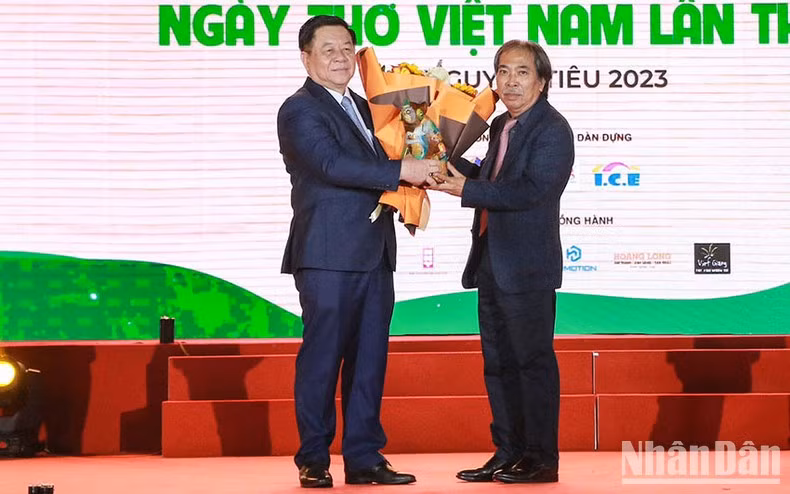 Secretary of the Party Central Committee Nguyen Trong Nghia (L) receives a gift of a cat sculpture by artist Le Dinh Nguyen, from Chairman of Vietnam Writers’ Association Nguyen Quang Thieu.