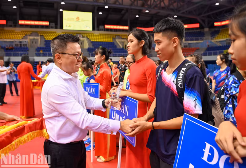 Editor-in-chief of Nhan Dan Newspaper Le Quoc Minh presents insignias to participating athletes.