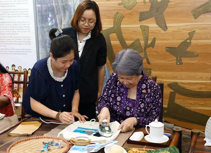 Ho Ching, the spouse of Singapore's Prime Minister Lee Hsien Loong, experiencing making fabric paintings from scrap silk under the guidance of Vun Art members in Hanoi.