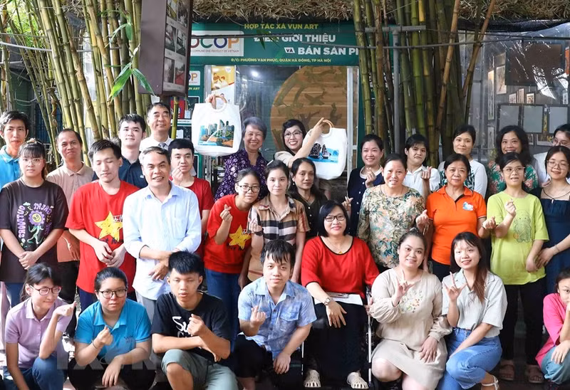 Le Thi Bich Tran (right), the spouse of Prime Minister Pham Minh Chinh, and Ho Ching, the spouse of Singapore's Prime Minister Lee Hsien Loong, take souvenir photos with members of the Vun Art Cooperative.